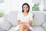 Smiling young dark haired woman in white clothes listening to music