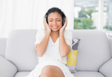 Peaceful young dark haired woman in white clothes listening to music