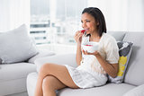 Lovely young dark haired woman in white clothes eating strawberries