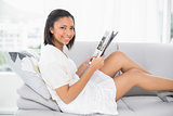 Casual young dark haired woman in white clothes reading a magazine