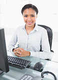 Smiling young dark haired businesswoman looking at camera