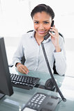 Smiling young dark haired businesswoman answering the telephone