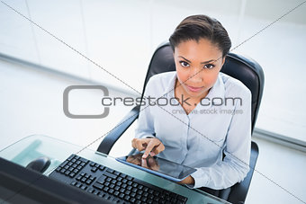 Serious young dark haired businesswoman using a tablet pc