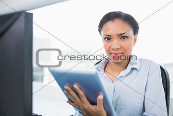 Stern young dark haired businesswoman using a tablet pc