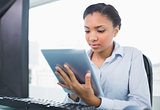 Concentrated young dark haired businesswoman using a tablet pc