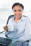 Content young dark haired businesswoman holding a mug of coffee