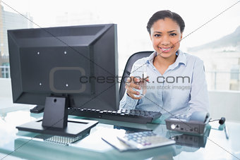 Pleased young dark haired businesswoman holding a glass of water