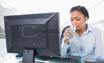 Relaxed young dark haired businesswoman drinking water