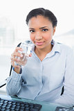 Smiling young dark haired businesswoman holding a glass of water