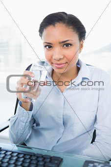 Smiling young dark haired businesswoman holding a glass of water