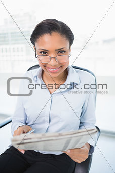 Attractive young dark haired businesswoman reading a newspaper