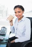 Amused young dark haired businesswoman drinking coffee
