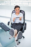 Cheerful young dark haired businesswoman filing her nails while sitting at her desk