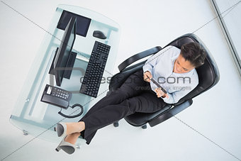 Attractive young dark haired businesswoman filing her nails while sitting at her desk