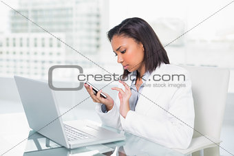 Serious young dark haired businesswoman using a mobile phone