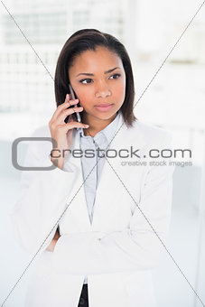 Thoughtful young dark haired businesswoman making a phone call