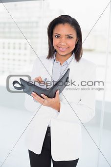 Cheerful young dark haired businesswoman filling her schedule