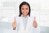 Pleased young dark haired businesswoman giving thumbs up