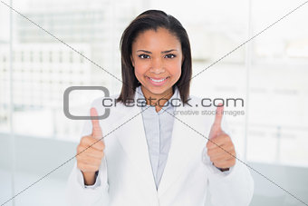 Pleased young dark haired businesswoman giving thumbs up