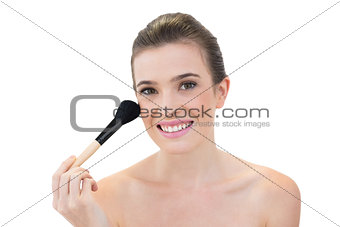 Cheerful natural brown haired model applying powder on her face