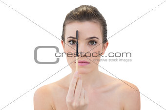 Stern natural brown haired model holding an eyebrow brush
