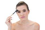 Concentrated natural brown haired model using an eyebrow brush