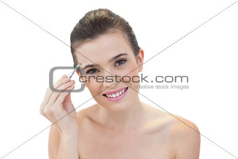 Pleased natural brown haired model plucking her eyebrows