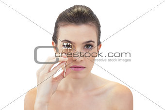 Unsmiling natural brown haired model using eyelash curler