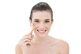 Joyful natural brown haired model holding an eyelash curler