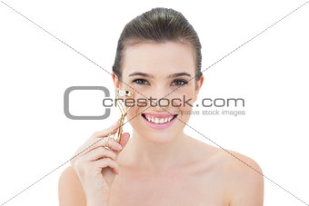 Joyful natural brown haired model holding an eyelash curler