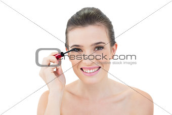 Joyful natural brown haired model applying mascara