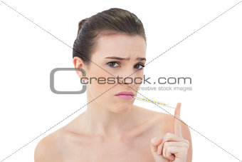 Frowning natural brown haired model using a thermometer
