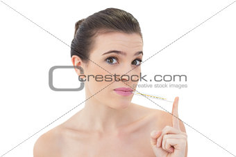 Upset natural brown haired model using a thermometer