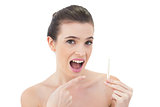 Surprised natural brown haired model pointing a thermometer with her finger