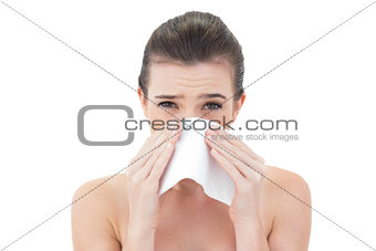 Upset natural brown haired model sneezing in a tissue