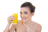 Amused natural brown haired model showing her glass of orange juice
