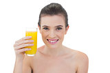 Content natural brown haired model holding a glass of orange juice