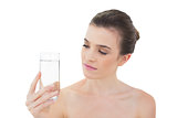 Peaceful natural brown haired model looking at a glass of water