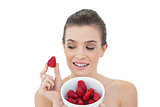 Gorgeous natural brown haired model showing a bowl of strawberries