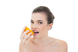 Relaxed natural brown haired model eating an orange