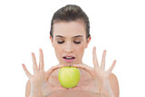 Concentrated natural brown haired model holding a green apple