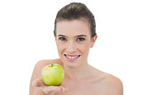 Gorgeous natural brown haired model offering a green apple