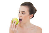 Calm natural brown haired model biting an apple