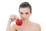 Stern natural brown haired model holding a red apple