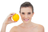 Laughing natural brown haired model holding an orange