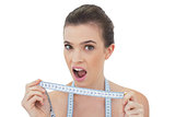 Funny natural brown haired model playing with a measuring tape