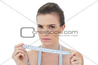 Frowning natural brown haired model holding a measuring tape