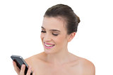 Amused natural brown haired model looking at her mobile phone