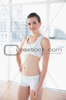 Content fit brown haired model in sportswear posing with a hand on the hip