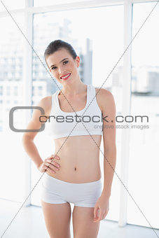 Amused fit brown haired model in sportswear posing with a hand on the hip